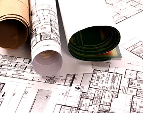 Rolled up building plans on top of a laid out plan